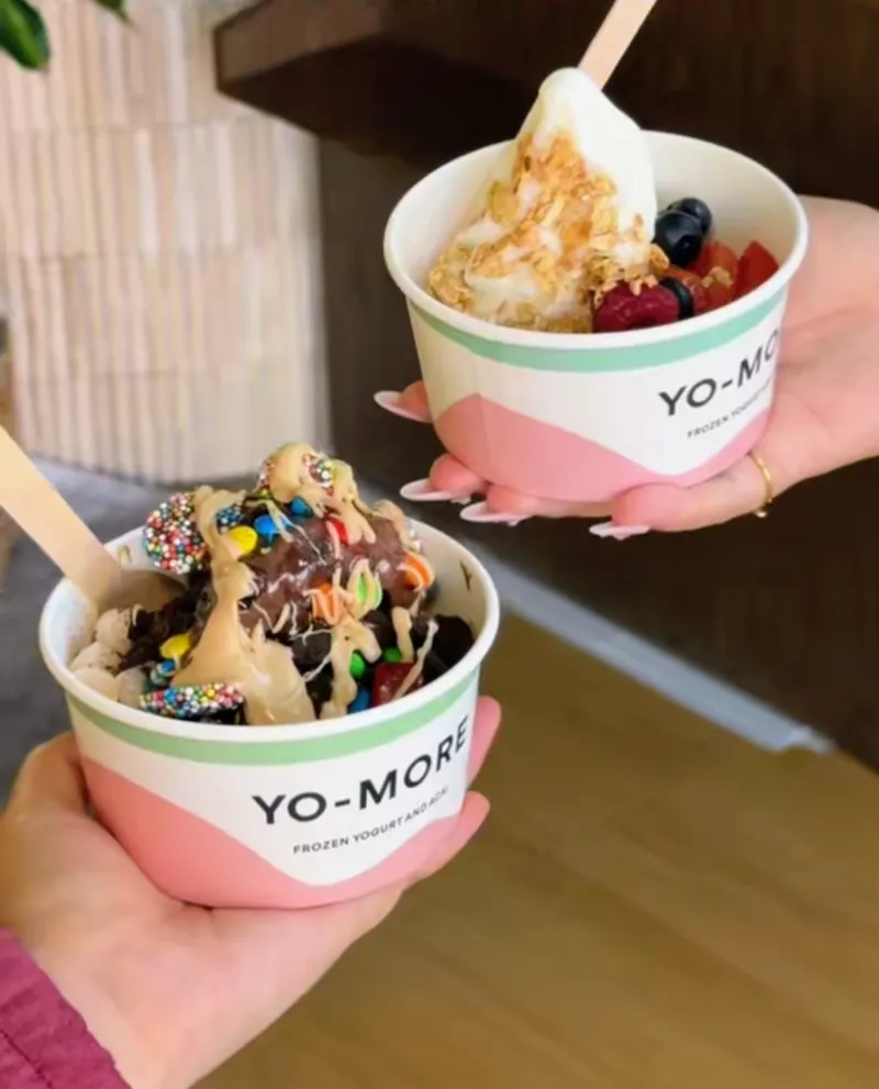 Two Yo More frozen yogurt cups loaded with toppings